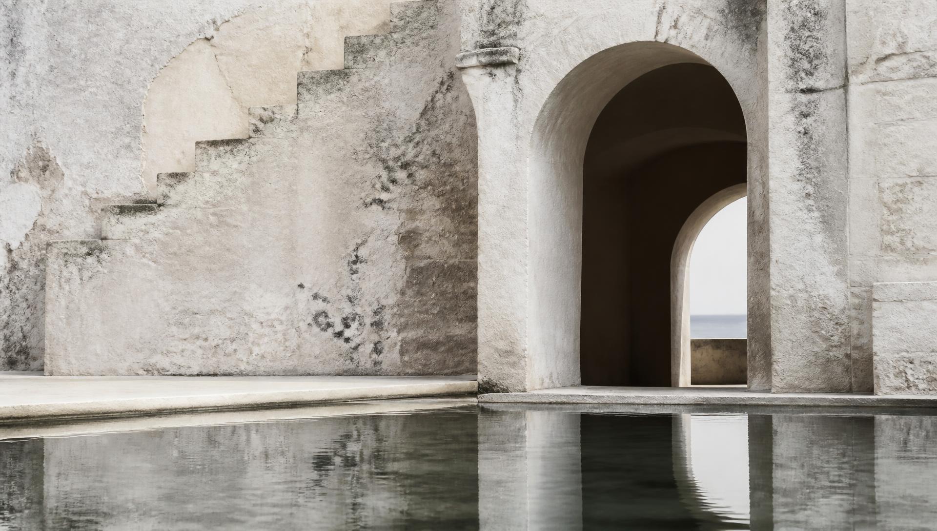 Pale limestone wall, arched passage and still water